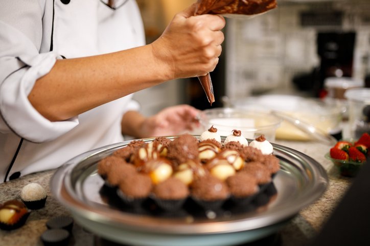 Confectioner decorating sweets with icing bag - beijinho and brigadeiro